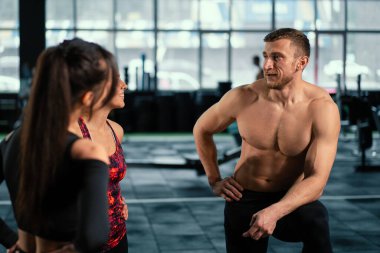 Atletik sporcu erkek sporcu, sıkı spor salonundaki eğitiminden sonra formda kızlarla iletişim kurar. Sağlıklı erkek ve kadın beden eğitimi egzersizinden sonra yoruldu..