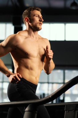 Erkek sporcu koşu bandında koşuyor.