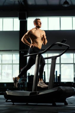 Erkek sporcu koşu bandında koşuyor.