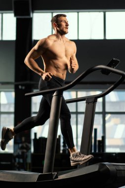 Erkek sporcu koşu bandında koşuyor.