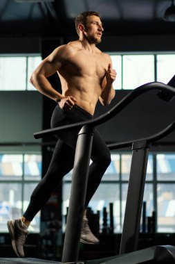 Erkek sporcu koşu bandında koşuyor.