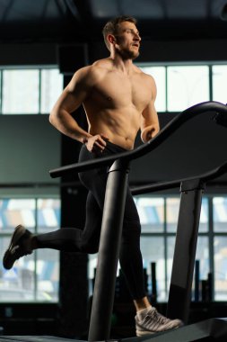 Erkek sporcu koşu bandında koşuyor.