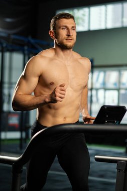 Erkek sporcu koşu bandında koşuyor.