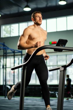 Erkek sporcu koşu bandında koşuyor.