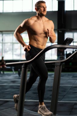 Erkek sporcu koşu bandında koşuyor.