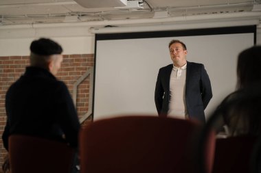 Şirketin genç iş adamı modern ofiste ofis personeli için finansal konferans sunuyor..