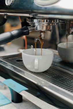 Profesyonel bir makineden bir fincana kahve dökülüyor. Kahveci filtre tutacağı kullanarak duble espresso yapıyor. Taze kahve akıyor. Sabahları kavrulmuş sade kahve içmek.