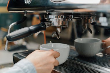Profesyonel bir makineden bir fincana kahve dökülüyor. Kahveci filtre tutacağı kullanarak duble espresso yapıyor. Taze kahve akıyor. Sabahları kavrulmuş sade kahve içmek.