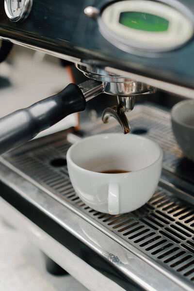 Наливание кофе поток из профессиональной машины в чашку. Бариста делает двойной эспрессо, используя держатель фильтра. Поток свежего молотого кофе. Пить жареный черный кофе по утрам