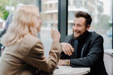 Genç bir çift kahve dükkanında vakit geçirir, şakalar yapar ve gülümserler.