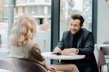 Genç bir çift kahve dükkanında vakit geçirir, şakalar yapar ve gülümserler.