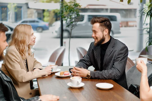 Man drinks filter coffee in the company of cheerful friends who communicate on weekends and spend time together at lunch in the cafeteria. Meeting in a public place. Friendship.