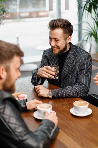 Man drinks filter coffee in the company of cheerful friends who communicate on weekends and spend time together at lunch in the cafeteria. Meeting in a public place. Friendship.