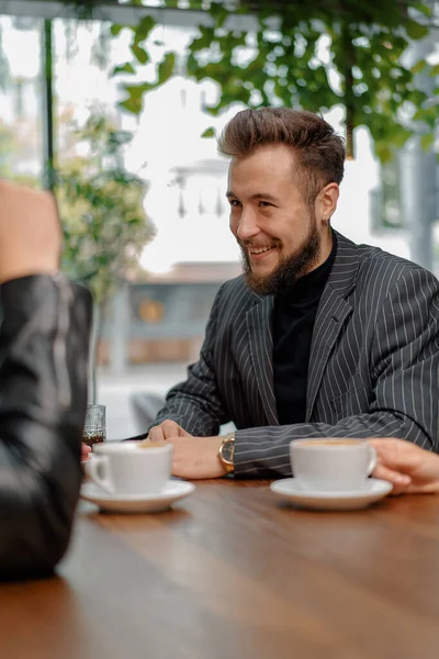 Bir adam hafta sonları sohbet eden neşeli arkadaşlarıyla kahve filtresi yudumluyor ve kafeteryada birlikte vakit geçiriyorlar. Halka açık bir yerde buluşmak. Arkadaşlık..