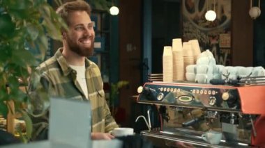 Handsome male barista gives coffee to a Man. Man buys coffee in a coffee shop.