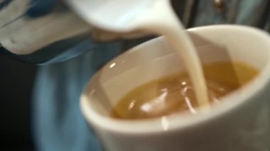 Barista steaming milk. barista prepares latte. coffee drink. latte. close up. barista whips milk in a pitcher with hot steam from coffee machine. process of making milk foam.