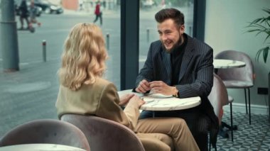Handsome stylish couple laughing on a date in a coffee shop. They tell stories and jokes.