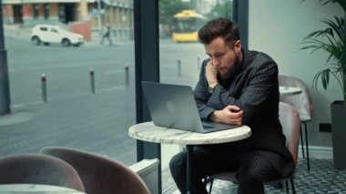 Bearded man is negotiating a zoom call in a coffee shop.Freelancer, businessman.