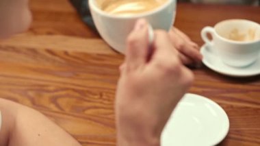 A white-skinned girl drinks filter coffee in a coffee shop in the company of cheerful friends.
