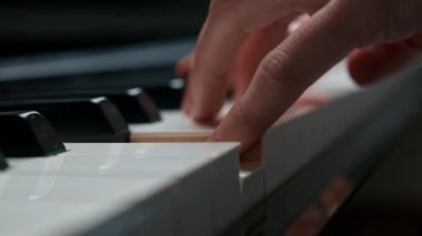 Piyano tuşuna seçici odaklanma ve piyano çalmak için parmaklar. Konser için müzik aleti ya da öğrenme müziği var. Sahnede piyano çalan çocuk müzisyenin eli kapalı..