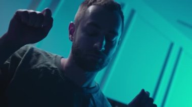 A music producer is dancing in a music studio. A man on drugs. Electonic music.