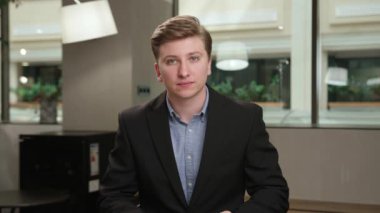 A male office worker communicates on zoom with colleagues at work (look at the camera), or conducts an interview