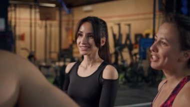 Beautiful women athletes communicate with bodybuilder in the gym, flirting
