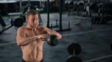 Young male athlete trains in the gym with dumbbells, crossfit, endurance