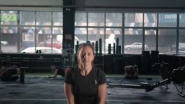 Young female athlete trains with a kettlebell in the gym, squats with a kettlebell