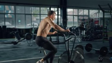 Young male athlete trains cardio on bike with fan, cardio training