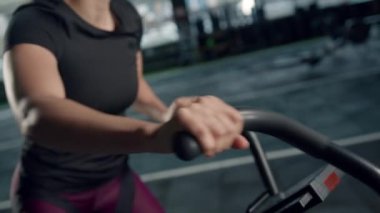 Young female athlete trains cardio on a bicycle with a fan, cardio training