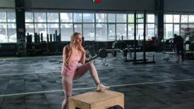 Young female athlete trains jumping on apple box in the gym, training legs