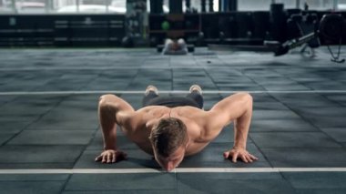 Young male athlete trains in the gym, push-ups from the floor, crossfit, endurance