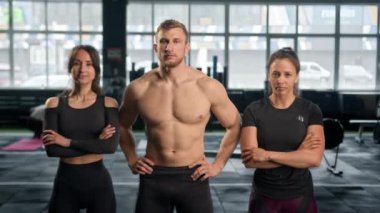 Portrait of group of young athletes looking at camera show thumbs up stand in fitness gym