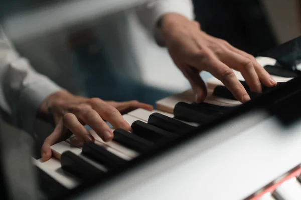 Refined woman pianist plays the piano with thin fingers, plays a musical instrument