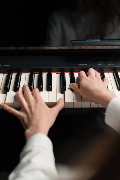 Refined woman pianist plays the piano with thin fingers, plays a musical instrument