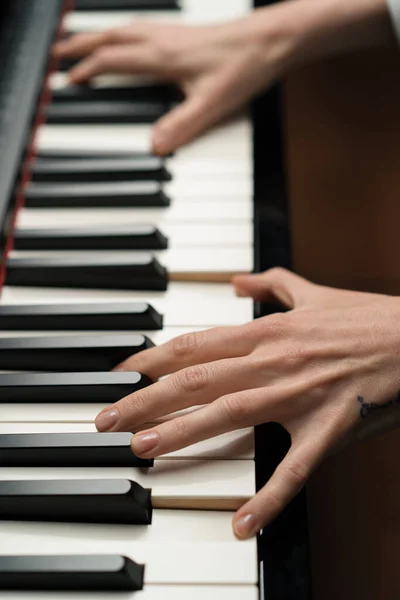 Refined woman pianist plays the piano with thin fingers, plays a musical instrument