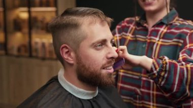 Barbershop: a woman barber cuts client's man's hair