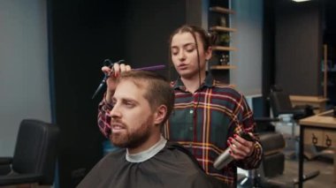 Barbershop: a woman barber cuts client's man's hair