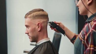 Barbershop: woman hairdresser cuts man's hair with razor