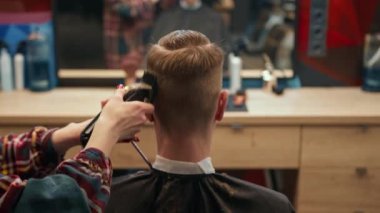 Barbershop: woman hairdresser cuts man's hair with razor