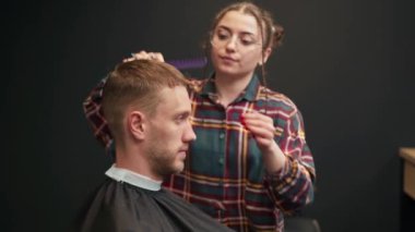 Barbershop: woman barber cuts a men's hair with scissors