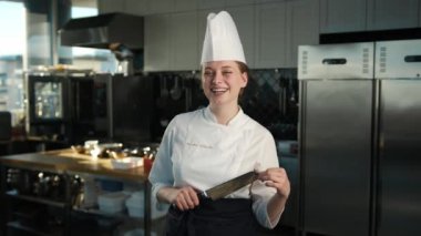 Professional kitchen, portrait: Female Chef holding knife and laughing ominously