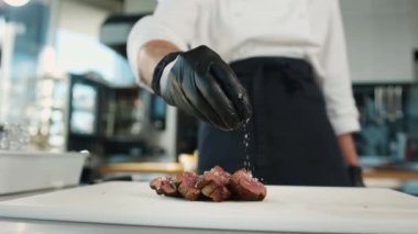 The chef sprinkles filet mignon with coarse salt. Serving food in restaurant.