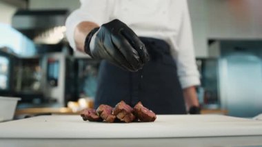 The chef sprinkles filet mignon with coarse salt. Serving food in restaurant.