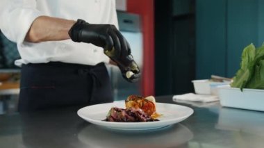 Close-up of a chef using flavor enhancer to make filet mignon and ratatouille tastier