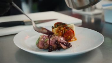 The chef pours sauce over the filet mignon. Serving food in restaurant.