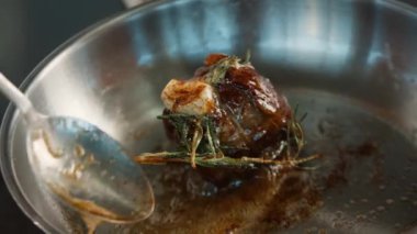 Close-up: Chef pouring sauce over a filet mignon while cooking