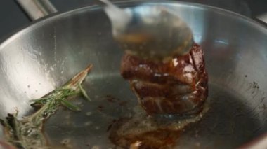 Close-up of a filet mignon being cooked in frying pan