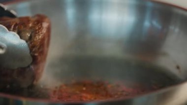 Close-up of a filet mignon being cooked in frying pan